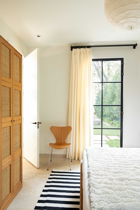 bedroom, black and white stripped rug, tiles, white linen, white throw rug, brown chair