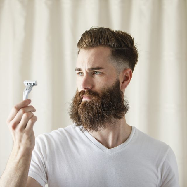 bearded caucasian man examining razor