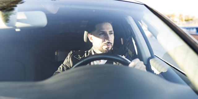 bearded male architect looking away while driving car