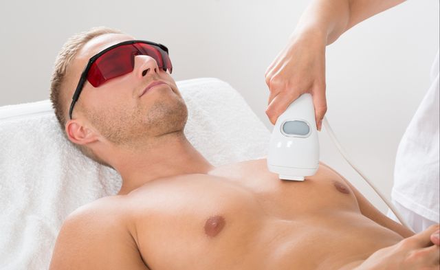 beautician giving laser epilation on man's chest