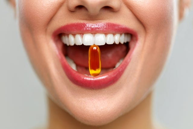 beautiful woman mouth with pill in teeth