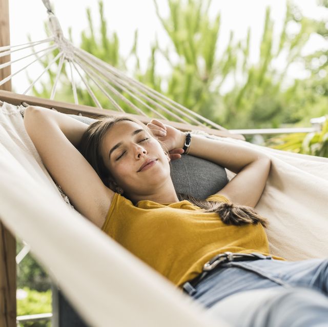 beautiful woman with arms raised napping on hammock in yard