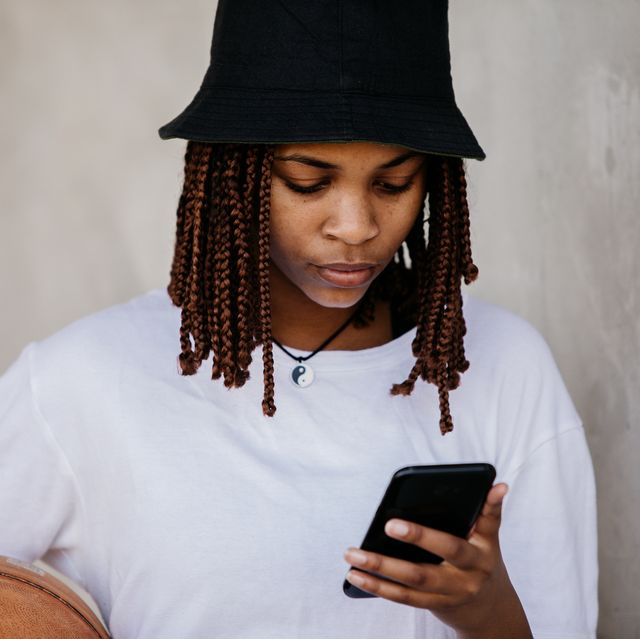 beautiful young woman reading her phone with basketball under arm