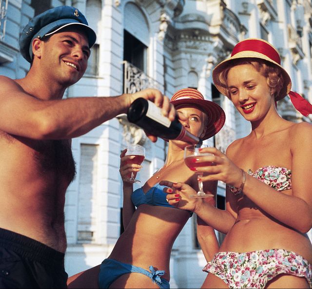 un hombre sirve alcohol a dos mujeres en la playa