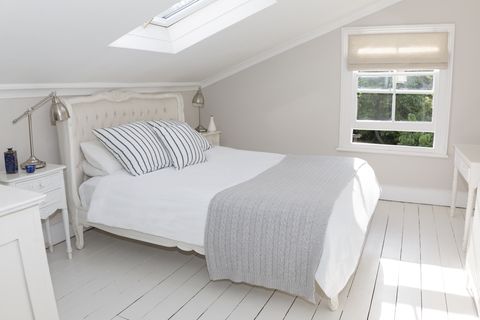 Bed in whitewashed attic bedroom