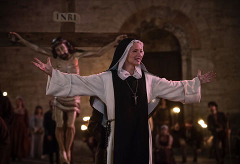 a nun raises her arms in the film benedetta