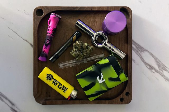 chillums and one hitters on a wooden tray with a lighter, grinder, and weed nugget