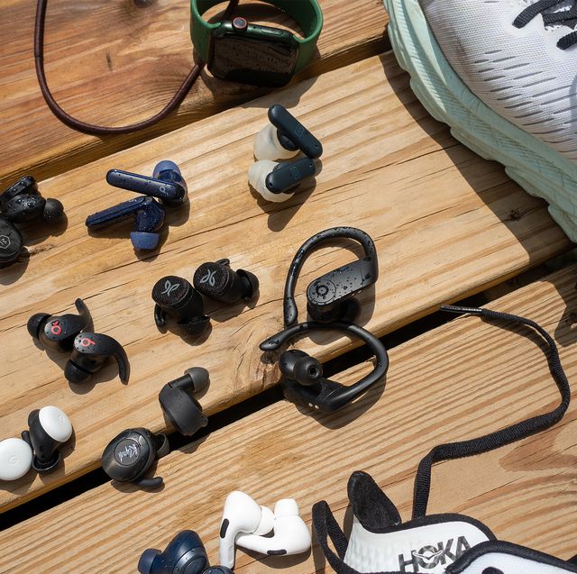 variety of headphones laying next to shoes and an apple watch