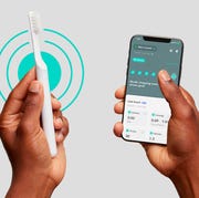 two hands holding a bluetooth quip toothbrush and phone