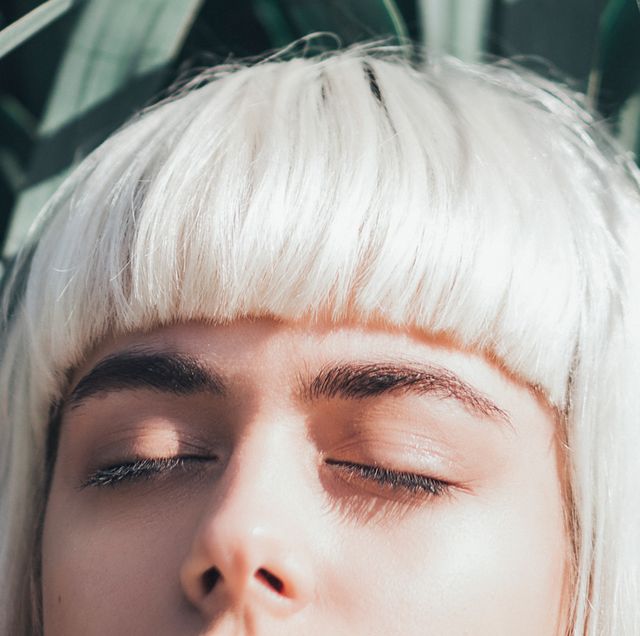 woman with bleached blonde hair and dark eyebrows with eyes closed