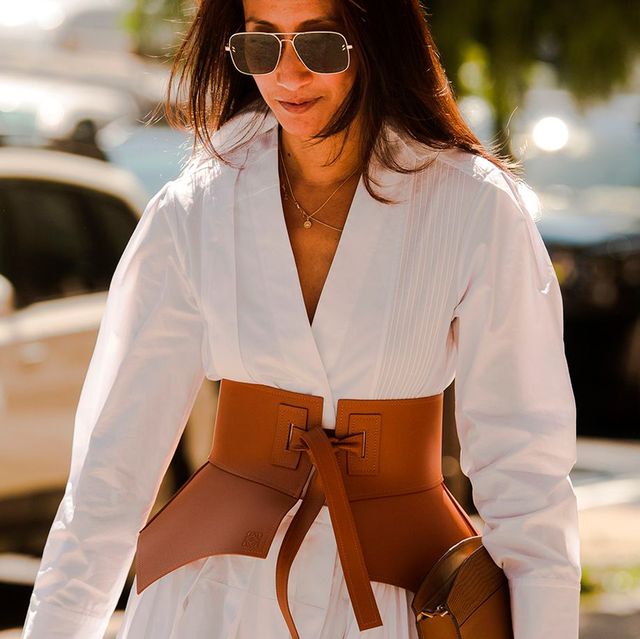 a woman at fashion week wears a white long sleeve flowy dress cinched with a belt in a roundup of the best flowy dresses for women 2022