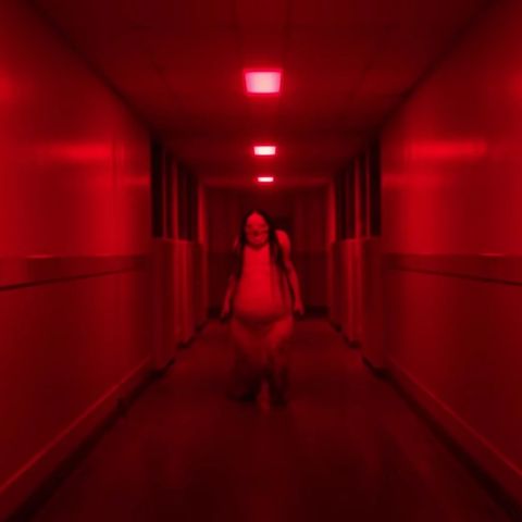 a monster stands at the end of a red hallway in a scene from scary stories to tell in the dark, a good housekeeping pick for best halloween movies on netflix