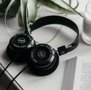 grado black headphones laying against white counter with a candle and book