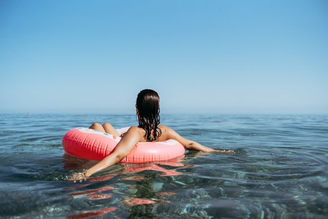 young woman in a sprinkled doughnut float at the beach sunset summertime