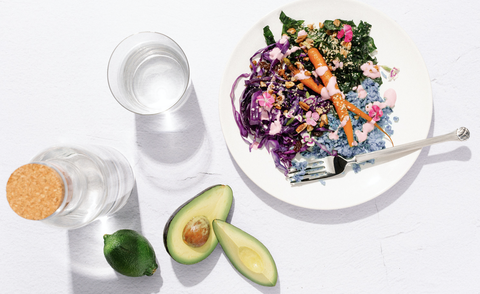 a colorful meal of cabbage, carrots, kale, cauliflower rice and avocado on a white background from sakara life, a good housekeeping pick for best healthy meal delivery service
