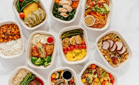 an assortment of meals including pork tenderloin and chicken entrees in meal prep containers on a white countertop from territory foods, a good housekeeping pick for best healthy meal delivery service