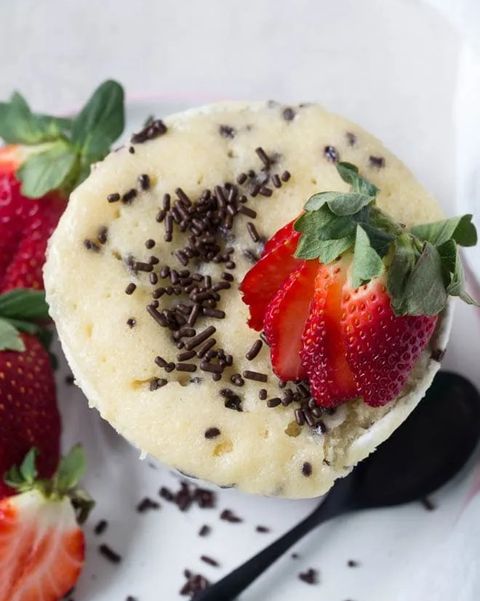 vanilla mug cake with chocolate sprinkles and a sliced strawberry on top