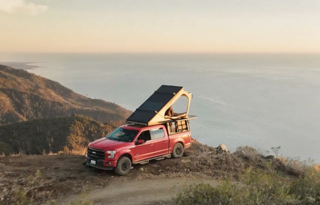 a truck on a mountain with an overlanding tent over looking the ocean