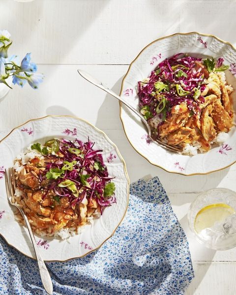 slow cooker gingery chicken with cabbage slaw served over rice on two plates with forks
