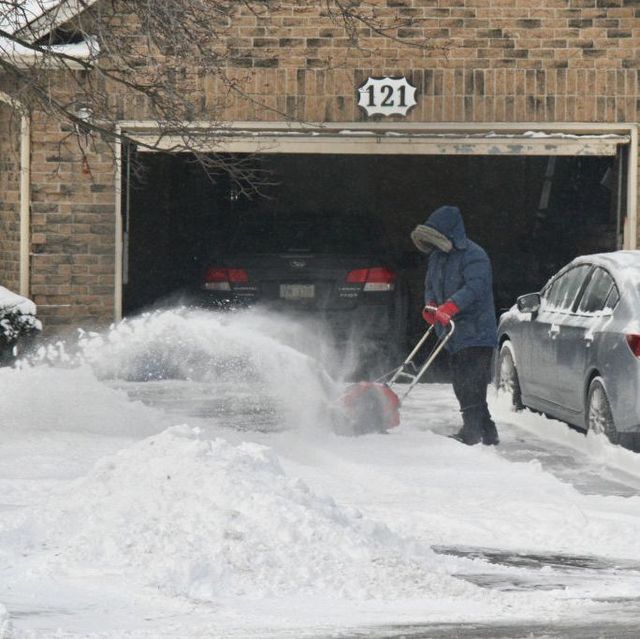 person using snow blower in drive way
