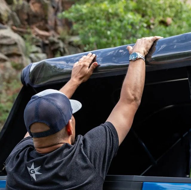 man accessing truck bed through an open soft truck topper panel