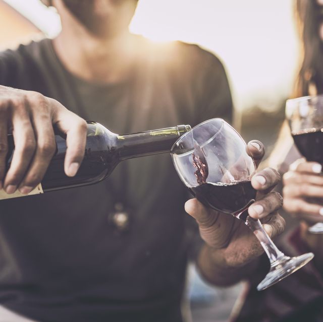 close up of a couple drinking wine outdoors while man is pouring it into a glass subscription