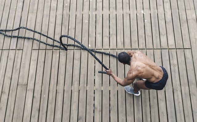 afro american muscular man, exercising with heavy ropes photo of handsome man with perfect body strength and motivation aerial view