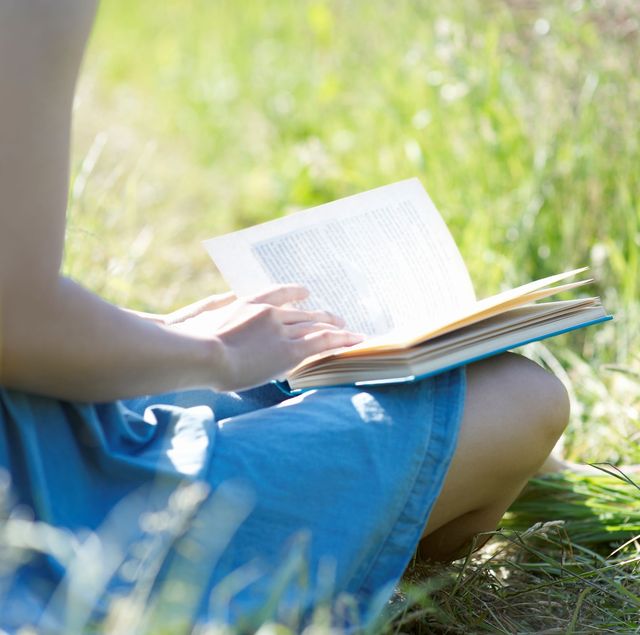 vrouw leest boek in het gras bij mooi weer