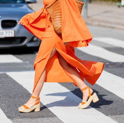 a woman wears a pair of espadrille sandals while crossing the street