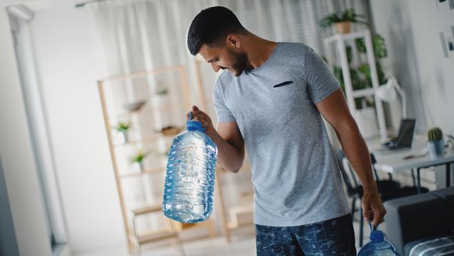 man traint biceps met waterflessen thuis
