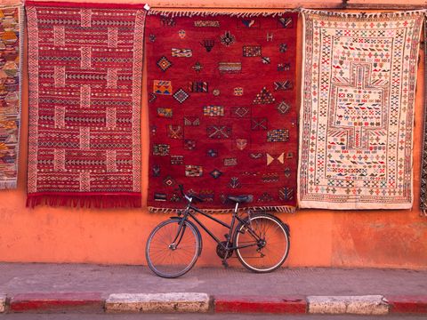 Bicycle parked at wall under hanging carpets with traditional patterns. Marrakesh, Morocco