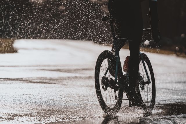 fietser in de regen met een opspattende straal druppels achter zich