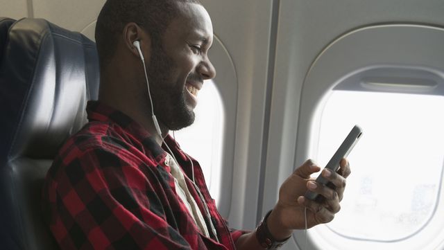 black man listening to earbuds on airplane