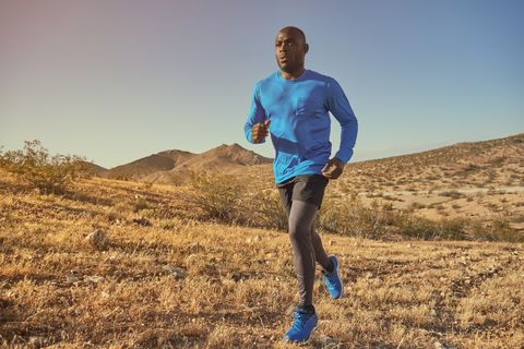 Black man runs across hills