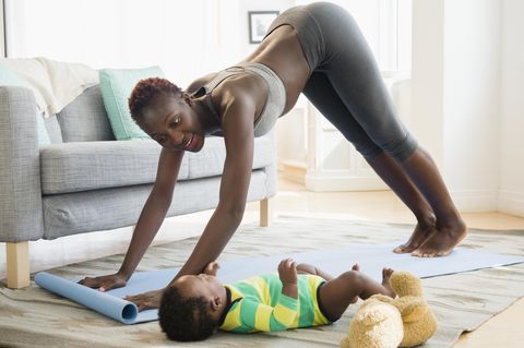 Black mother doing yoga with her baby boy in the living room