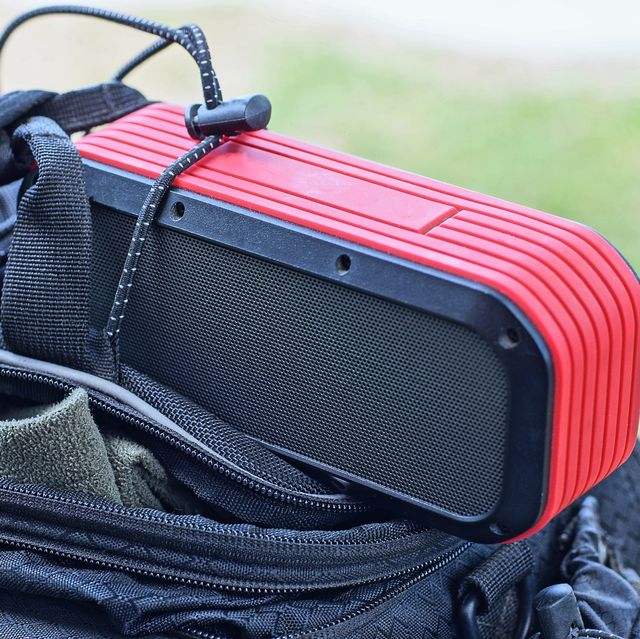 black red portable speaker lies on an open bag
