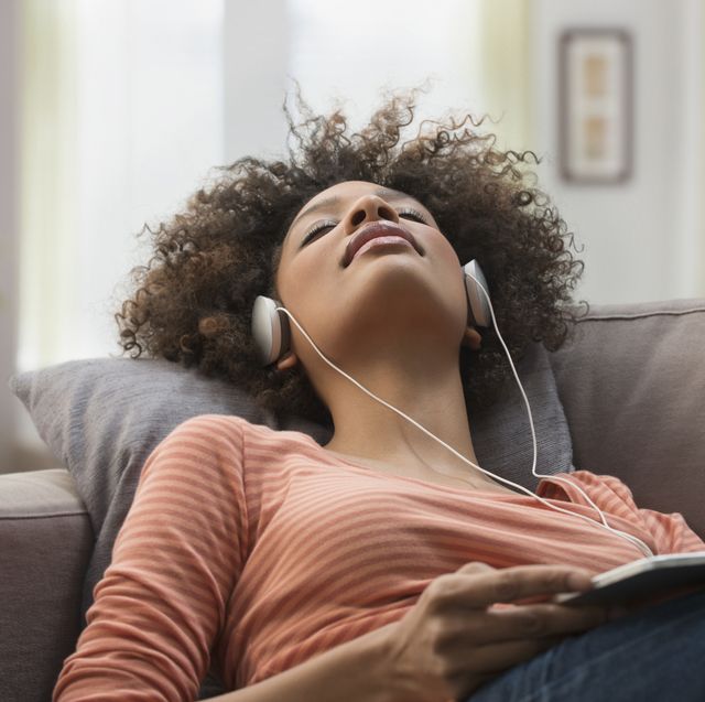 woman listening to headphones on sofa