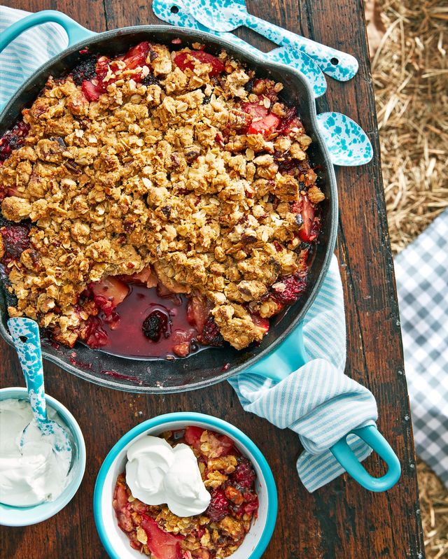 a cast iron pan with apple blackberry crumble and a bowl of sour cream whip