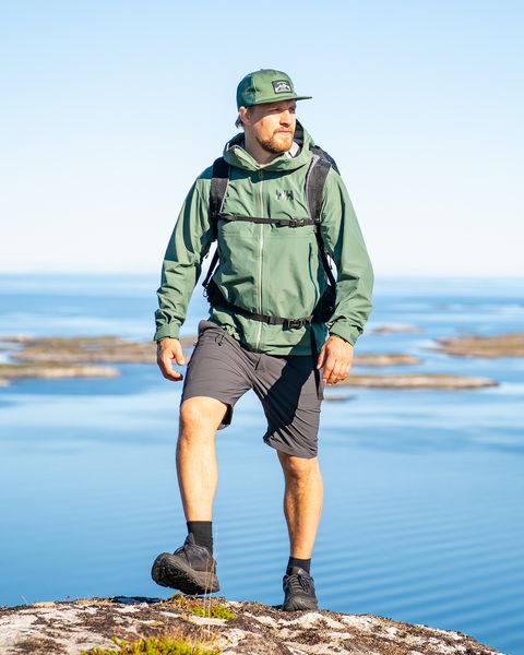 man wearing helly hansen ss23 new collection walking on rock overlooking ocean