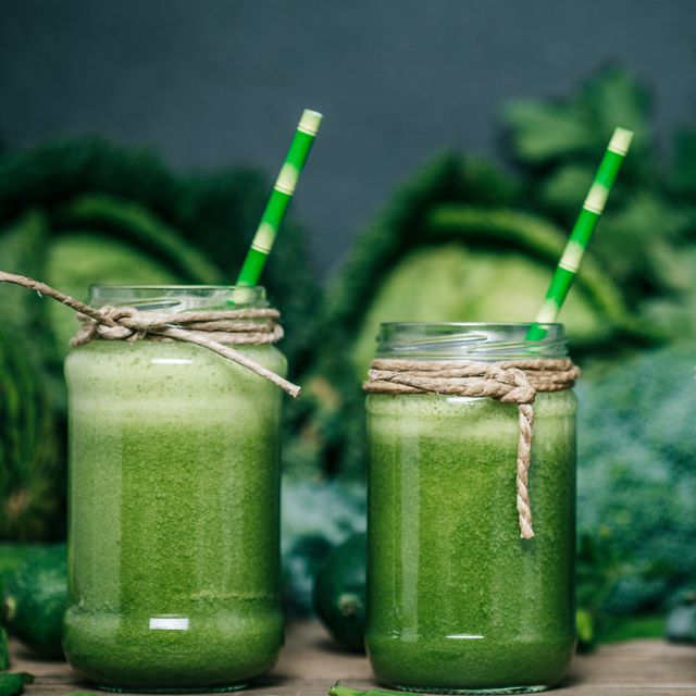 blended green smoothie with ingredients on wooden table