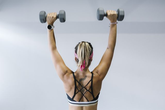 blonde woman training with dumbbells in gym
