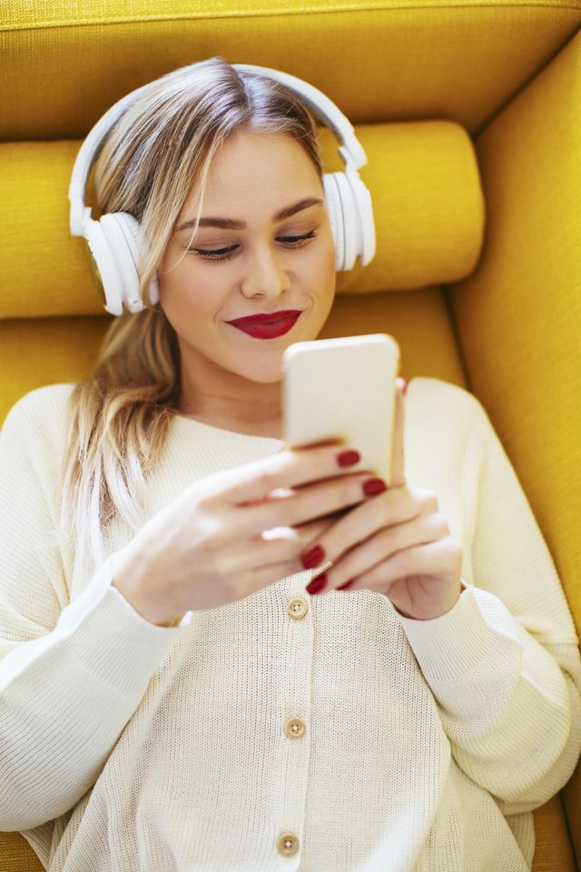 blonde woman with headphones using smartphone at home