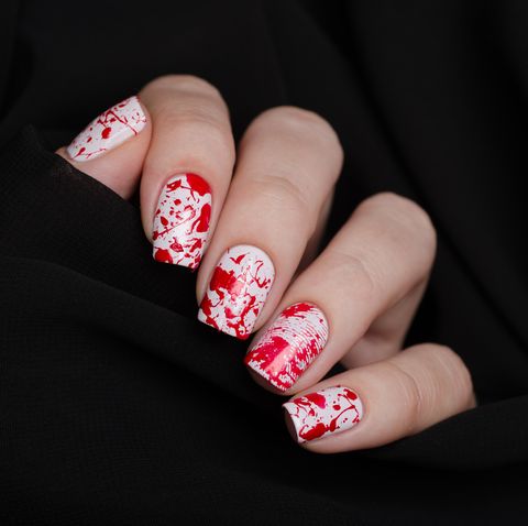 bloody manicure for halloween with drops of blood, and a fingerprint with a knife on a black background