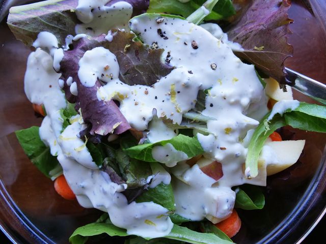 blue cheese dressing drizzled on top of a simple green salad