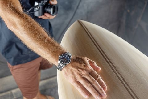 Nick Lavecchia wears a Seiko watch with his hand on the surfboard