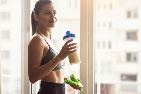 young female athlete drinking protein shake after workout