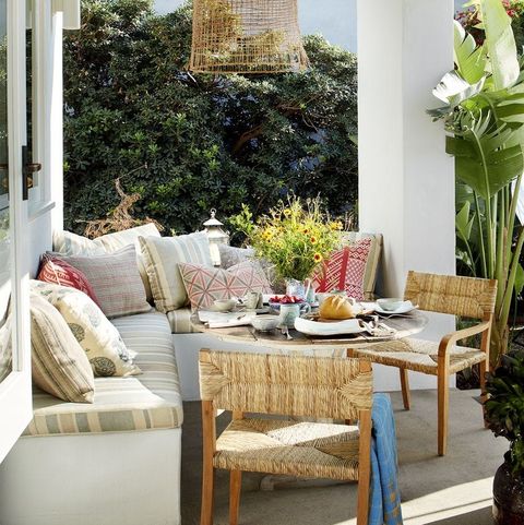 outdoor seating area with rush chairs round table and wraparound banquette with pillows