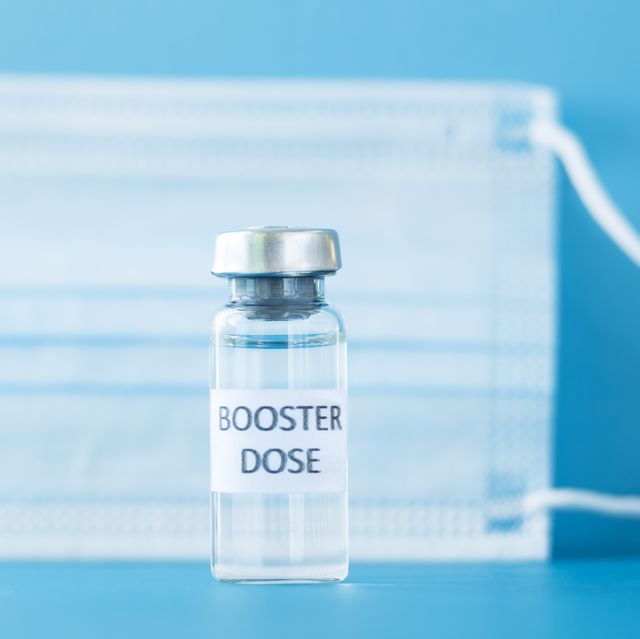 booster dose of coronavirus vaccine in a vial on blue background and medical mask