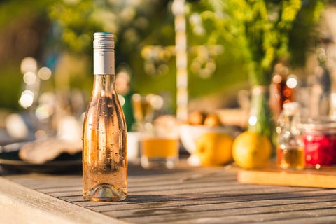 an unopened bottle of cold rosé wine on a midsummer dinner table in sweden focus on the dripping fresh bottle in the foreground