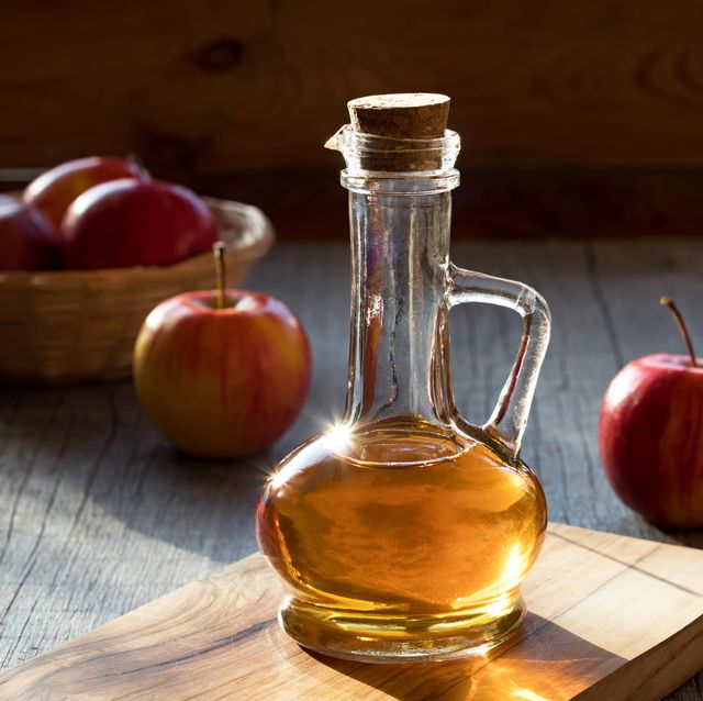 a bottle of apple cider vinegar with apples in the background